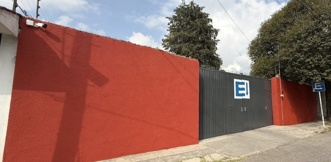 Muro rojo característico con reja gris y letrero E de estacionamiento